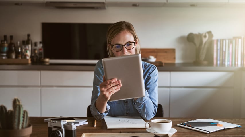 Kvinde sidder med ipad i køkken