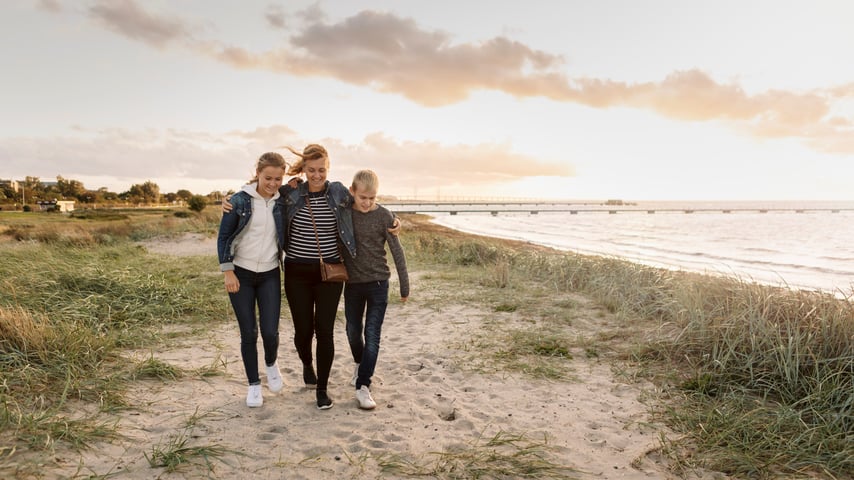 Familie går ved strand